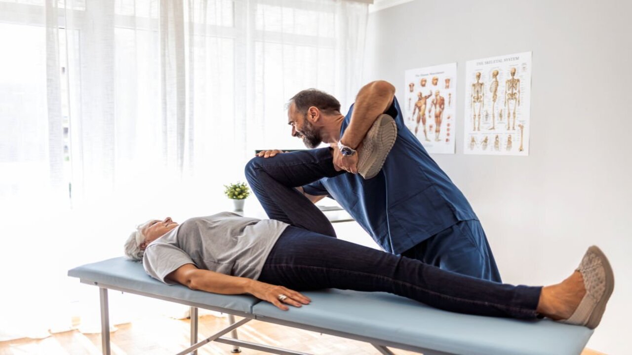 Male Doctor Chiropractor Fixing Womans Leg with Hands Movements